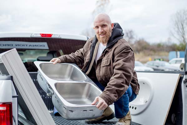 A community member in a pickup truck dropping off and donating a double sink