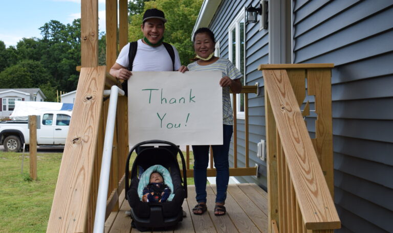 A Habitat family holding a homemade Thank You sign