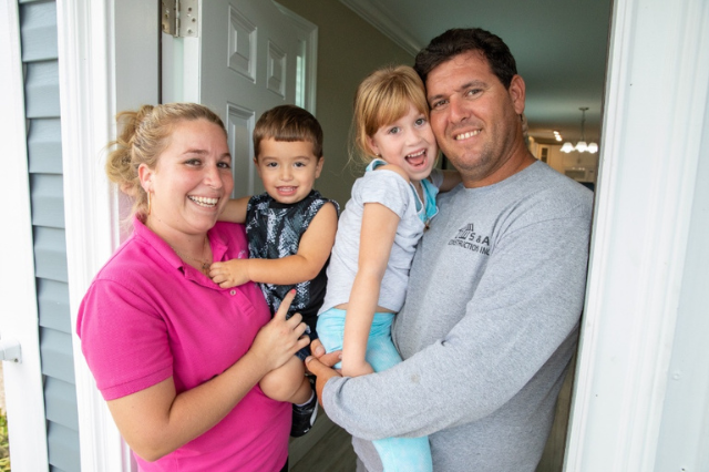 A family of four smiling in their doorway