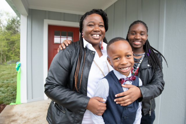 A Habitat family smiling on their porch