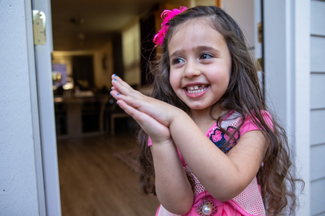 A sweet girl smiling in the doorway of her Habitat home