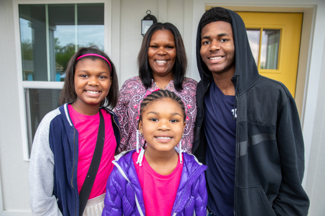 Habitat family smiling in front of their doorway