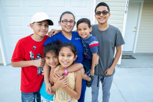 Habitat family smiling in their driveway