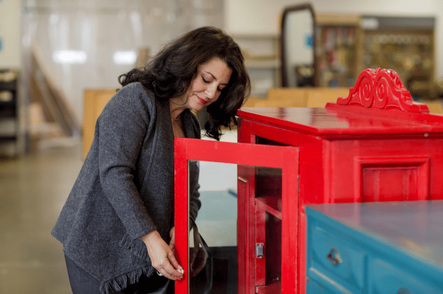 Woman looking at a red cabinet in a Habitat ReStore