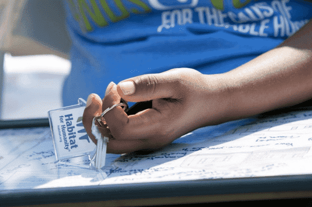 A hand holding the keys to a Habitat home